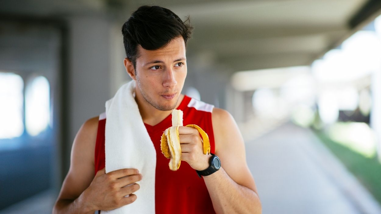 Un hombre comiendo un plátano. Canva