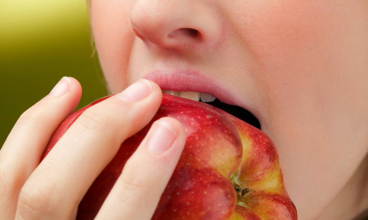Una mujer muerde una manzana