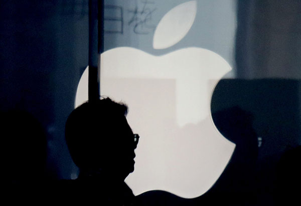 La silueta de un hombre se perfila en el logotipo de Apple en su tienda en Tokio (Japón)