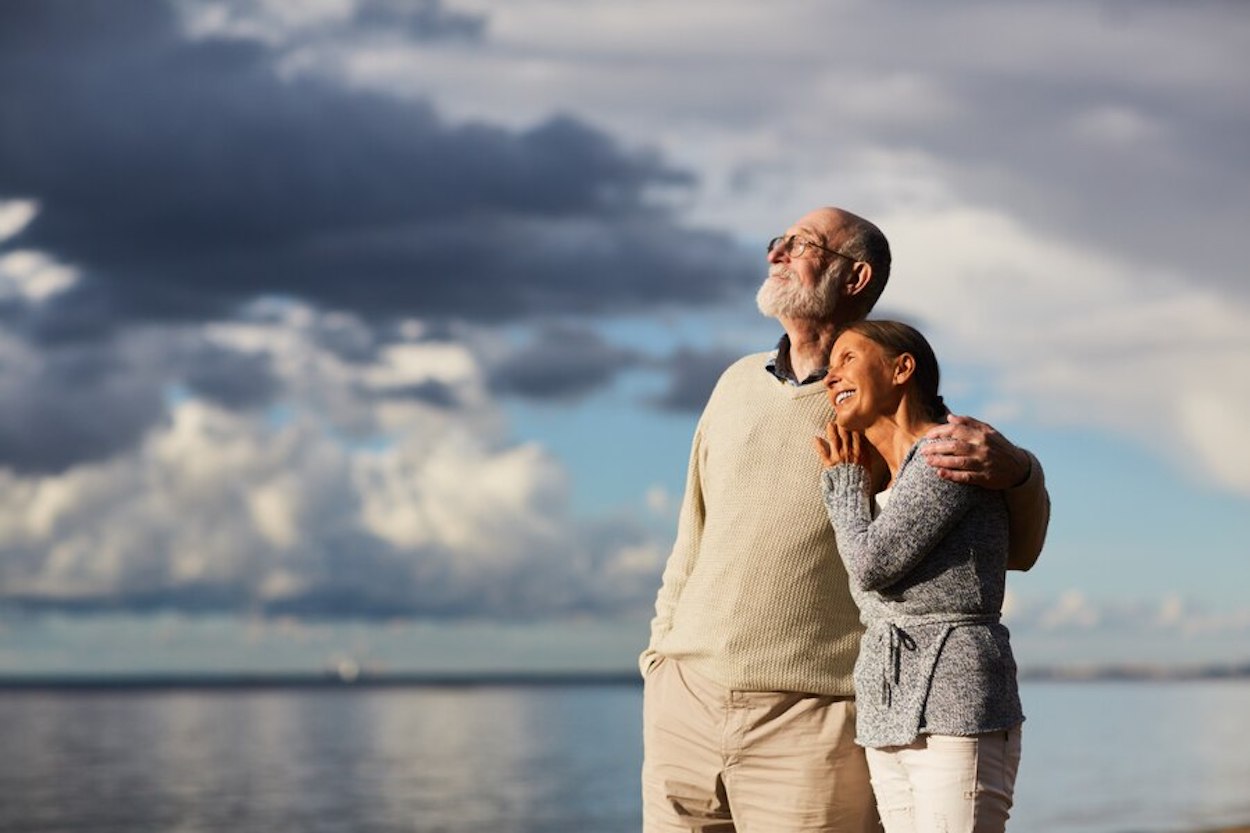 Pareja de jubilados viendo el horizonte junto al mar