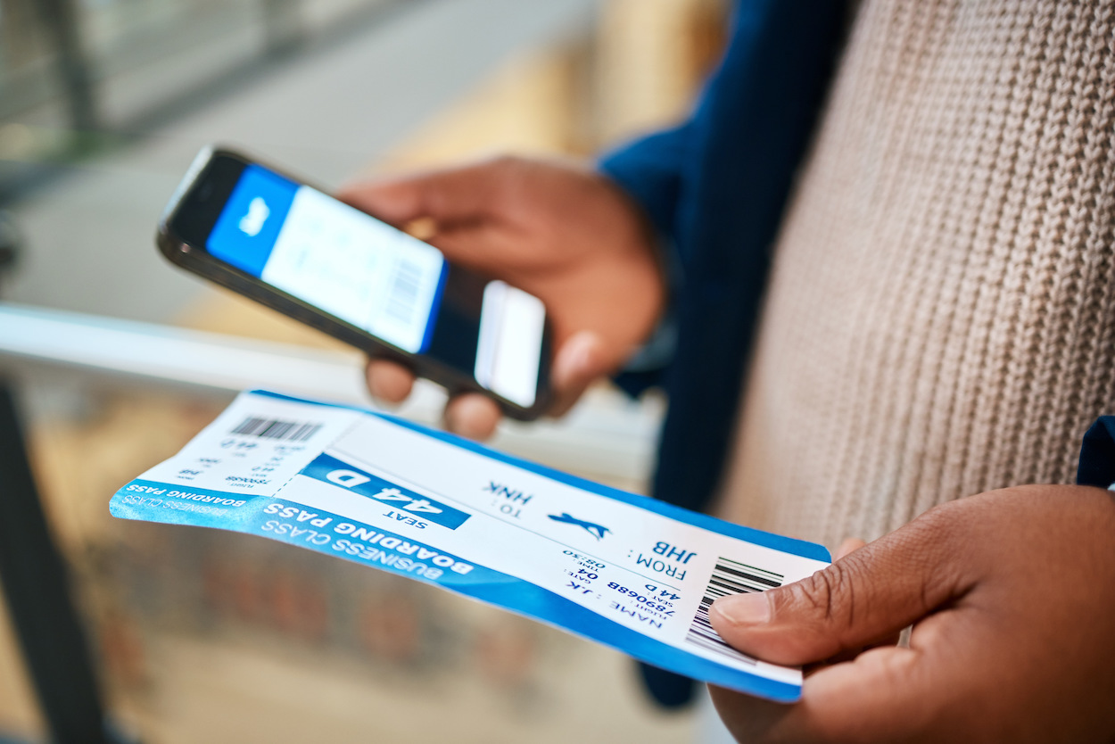 Hombre con un móvil y un ticket de viaje