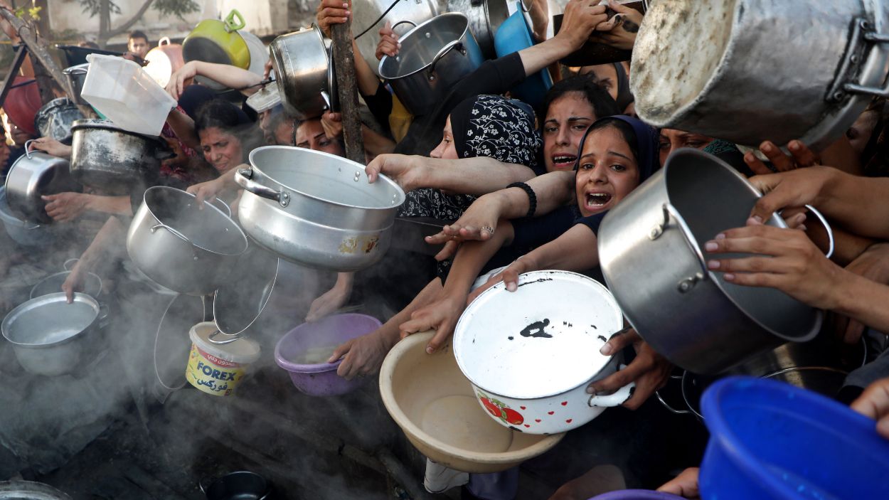 Palestinos esperan para recibir alimentos en el barrio de Al-Rimal, en el centro de la ciudad de Gaza. EP.