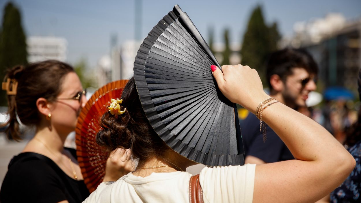 Una mujer se protege del elevado calor del verano con un abanico. EP.