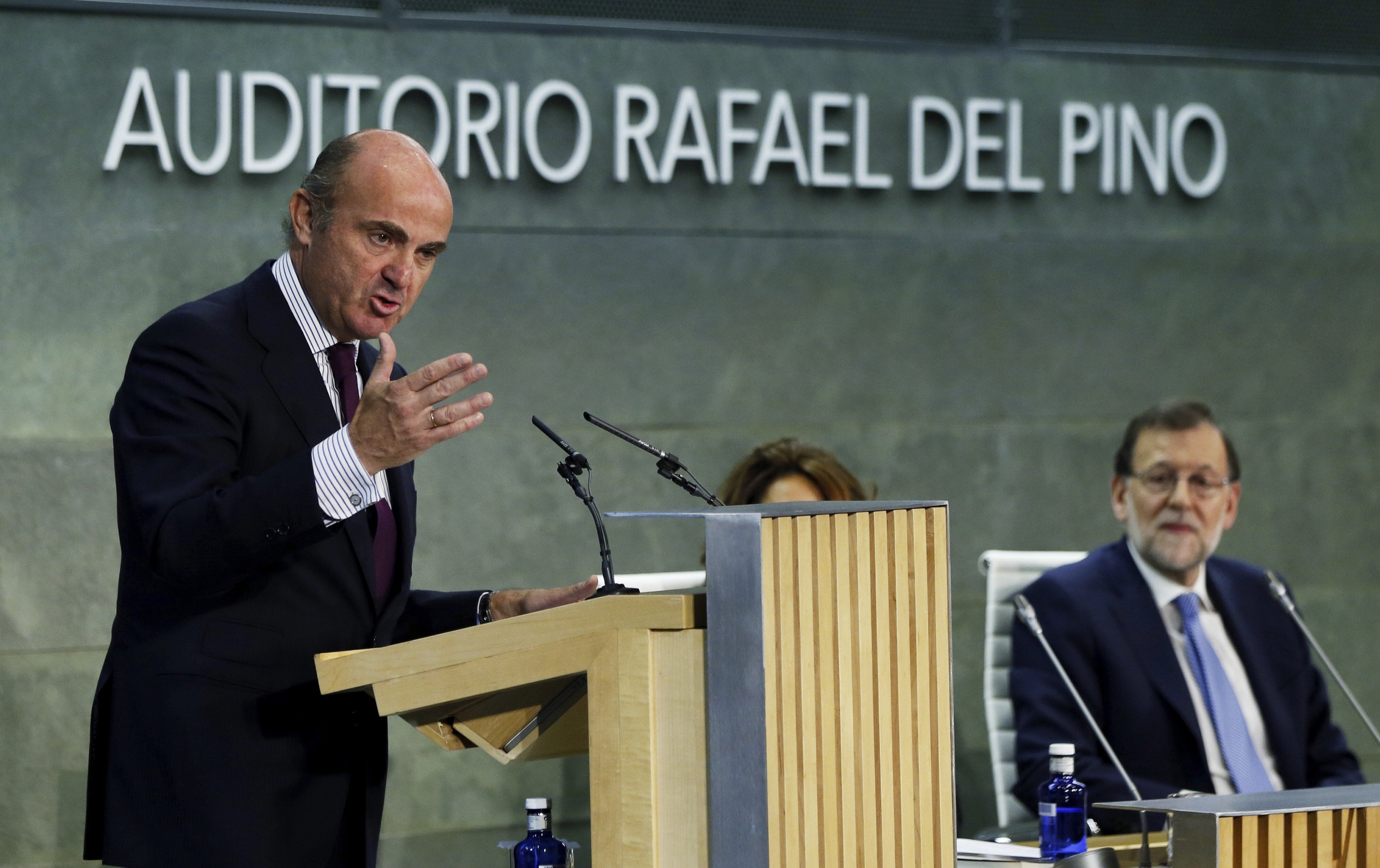 El ministro de Economía en funciones, Luis de Guindos, durante la presentación de su libro, "España amenazada". A la derecha, el presidente del Gobierno en funciones, Mariano Rajoy. 