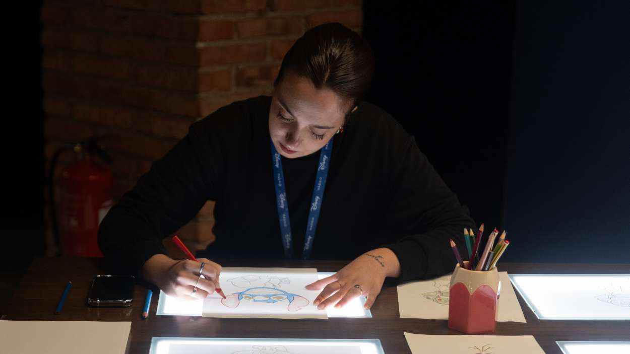Una mujer dibuja en Disney The Exhibition: 100 años de magia. EP