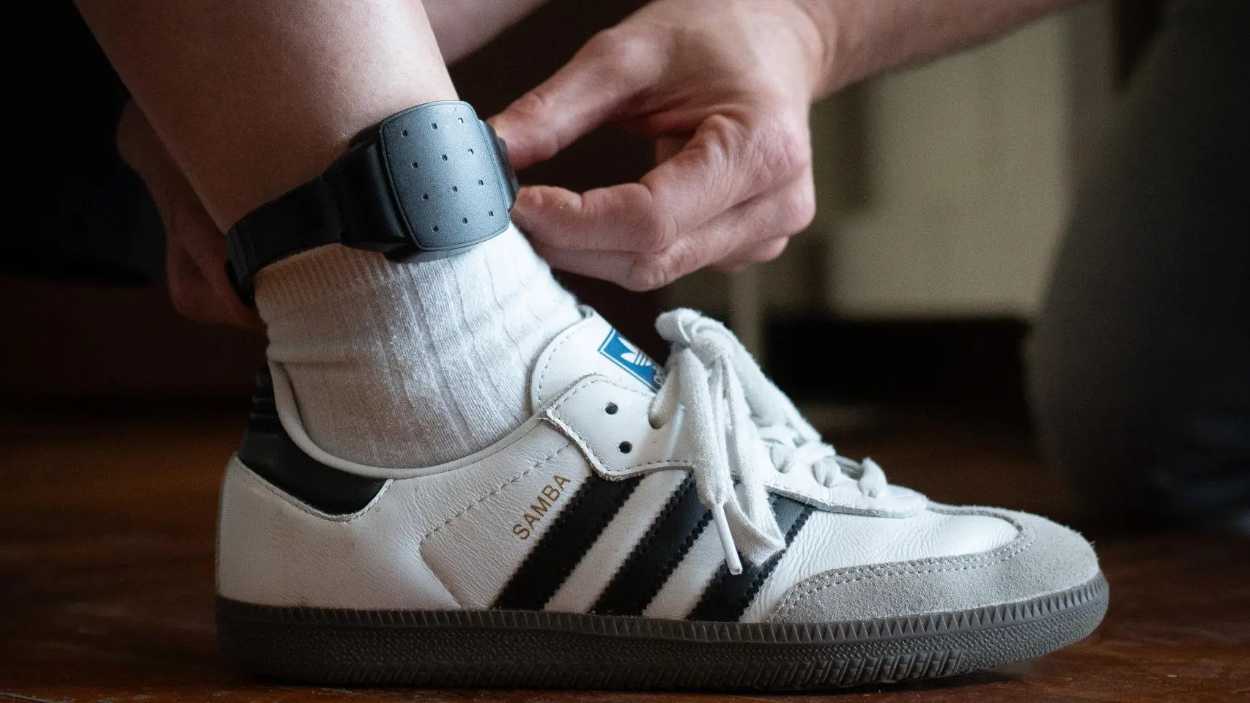 Una persona muestra una pulsera electrónica de geolocalización telemática. EP.