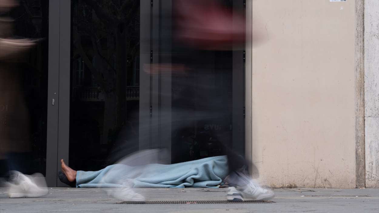 Varias personas pasan delante de una persona sin hogar, en el barrio del Raval de Barcelona. EP
