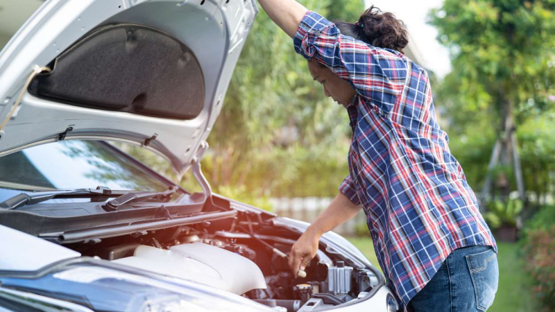 Un hombre revisando el motor de un coche Un hombre revisando el motor de un coche