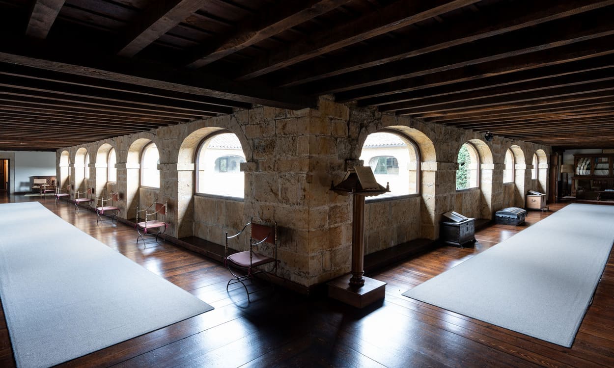 Galería interior con arcos de piedra y vigas de madera, testimonio de la arquitectura monástica original. PARADORES