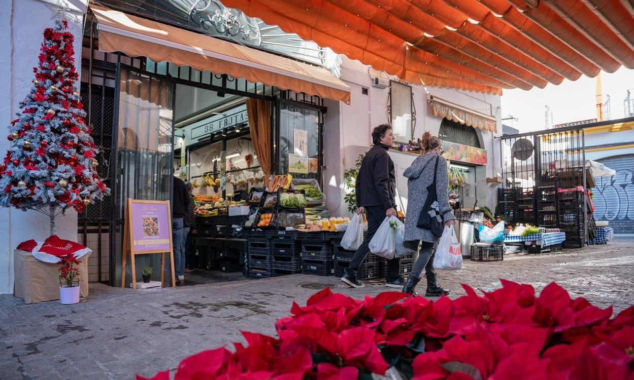 Varias personas en un mercado de Sevilla realizan sus comprar el día previo a la cena de Nochebuena. María José López / EP