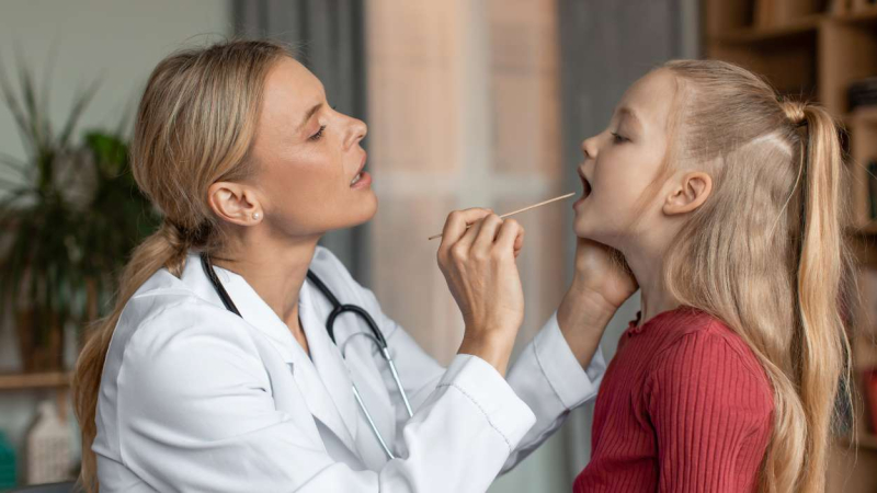 Una pediatra revisa la garganta a una niña