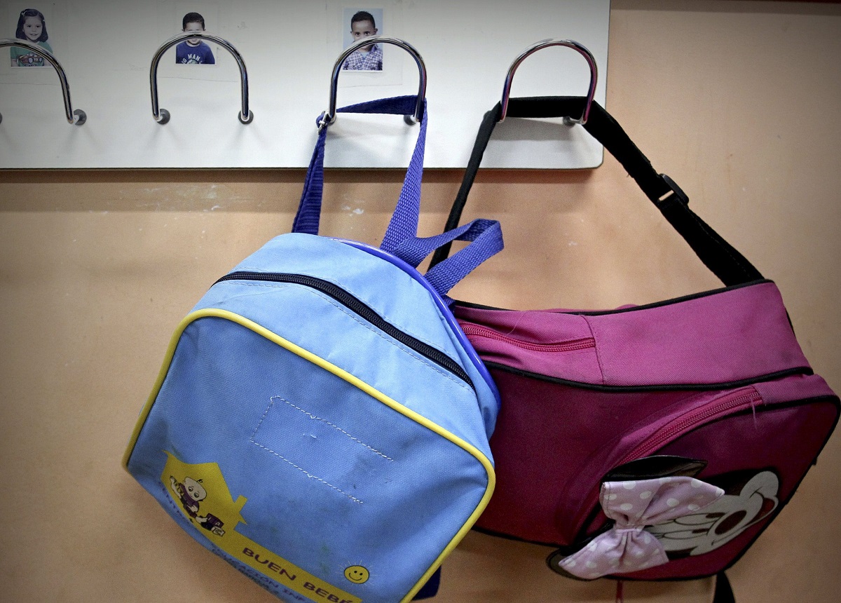 Dos mochilas escolares colgadas del perchero de un aula