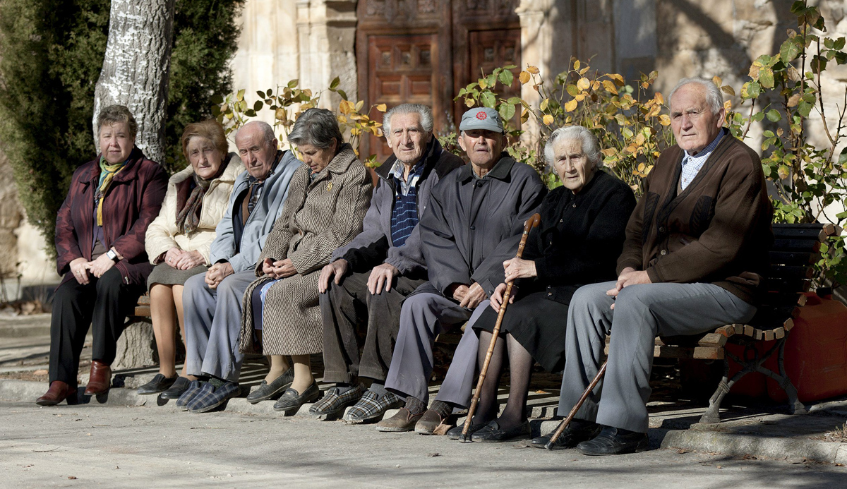 Varios ancianos toman el sol en unos bancos de Olmeda de la Cuesta, Cuenca