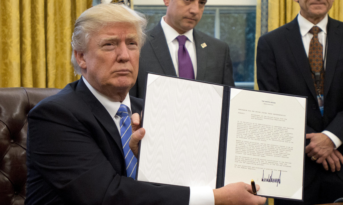 En la imagen, el presidente estadounidense, Donald Trump (c), muestra la orden ejecutiva para sacar a EE.UU. del acuerdo comercial TPP. 