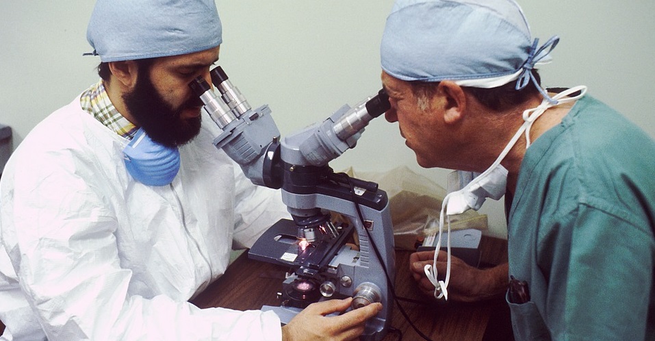 Dos doctores mirando a través de un microscopio