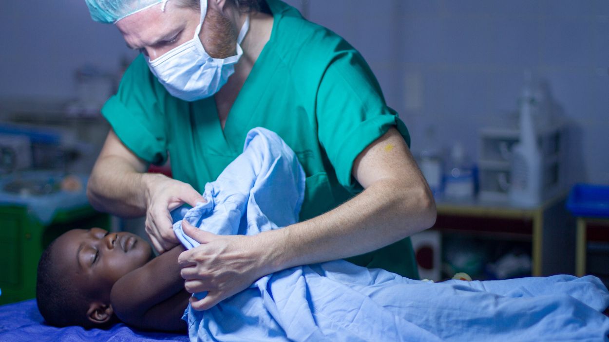 El cirujano Carlos de la Torre junto a un niño en una intervención quirúrgica en Togo