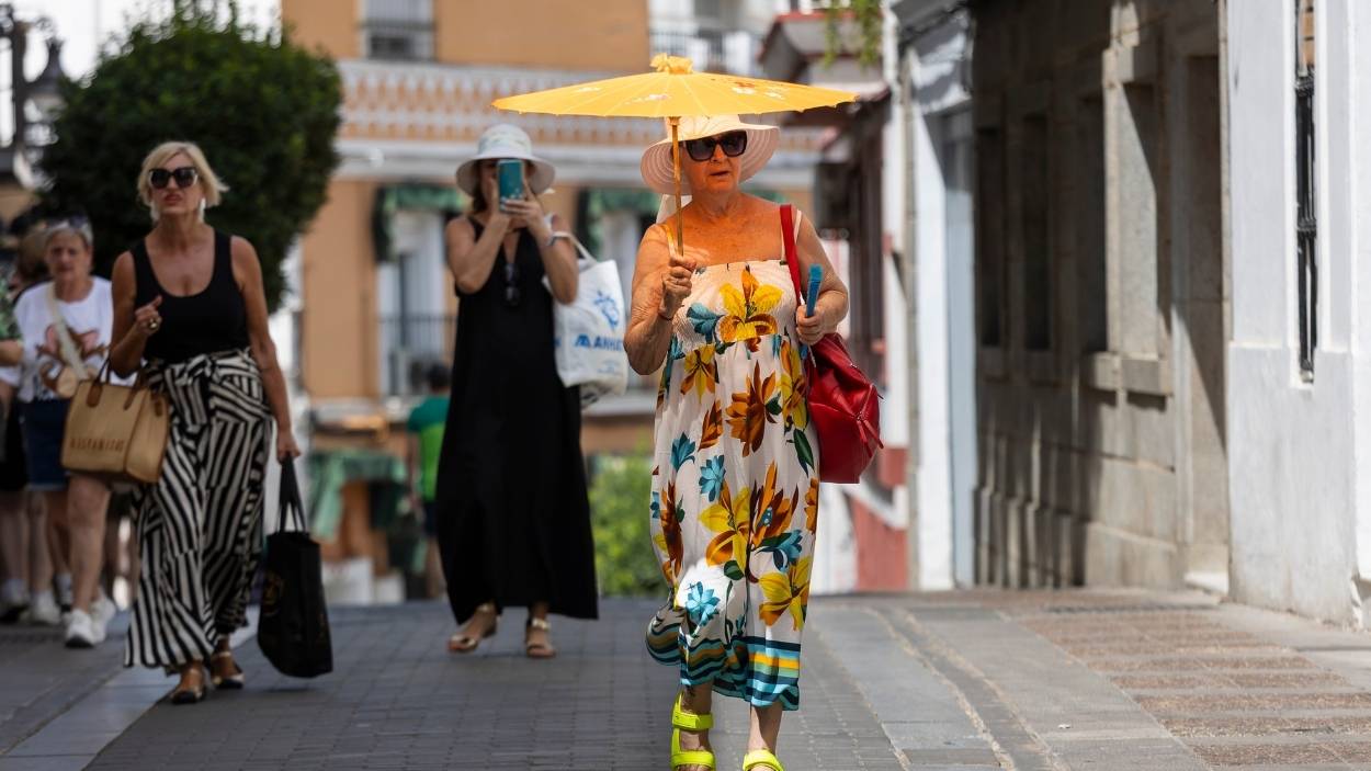 Una mujer se protege del sol con una sombrilla. EP.