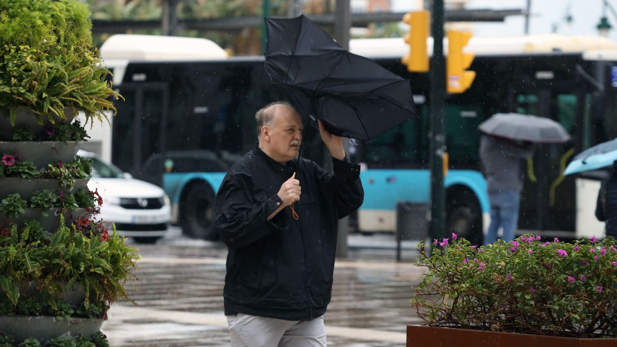 Imagen de transeúntes por el centro de Málaga protegiéndose de la lluvia y el fuerte viento. EP.