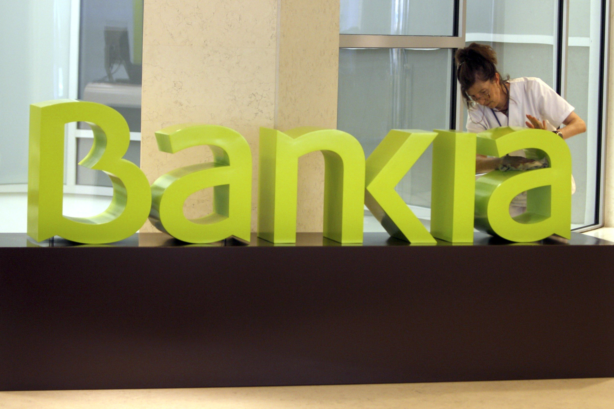 Una trabajadora limpia el logotipo de Bankia
