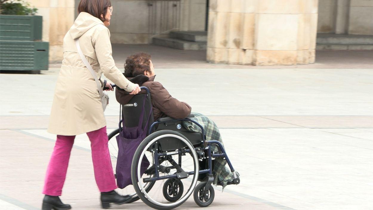 Una persona mayor en silla de ruedas paseando / Archivo EP