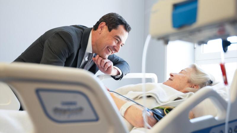 El presidente de la Junta de Andalucía, Juanma Moreno (i), junto a una paciente ingresada en el Hospital Virgen del Rocío / EP