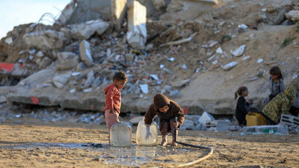 Niños palestinos cogen agua en una Gaza arrasada. EP/Ramzi Abu Amer.