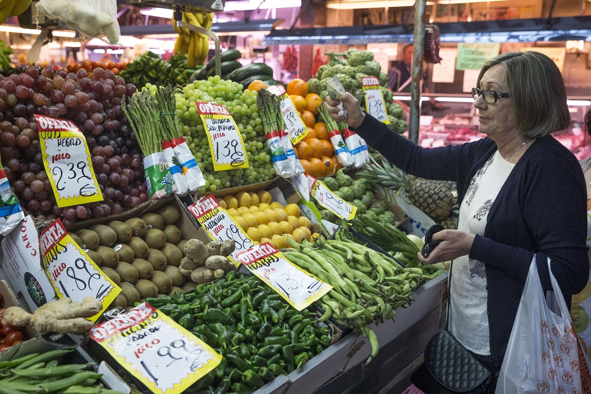 Una mujer hace su compra en una frutería del mercado Maravilla en Madrid