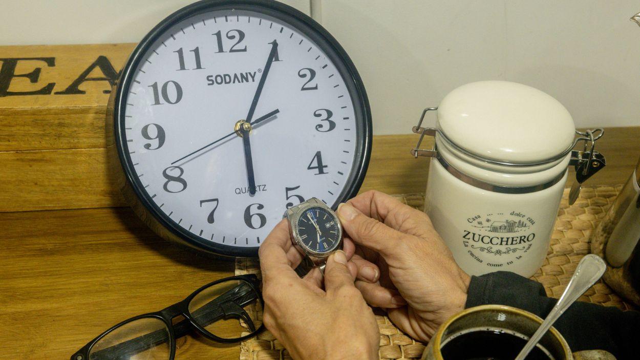 Una persona cambiando la hora en un reloj. EP.