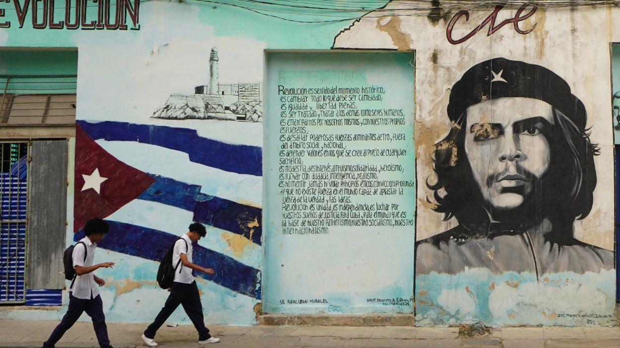 Dos personas caminan en La Habana frente a un mural del Che Guevara. EP/Archivo.
