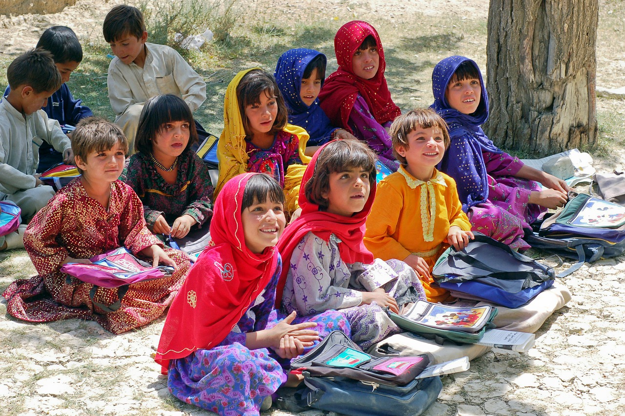 Un grupo de niños con pañuelo sentados en el suelo. Pixabay