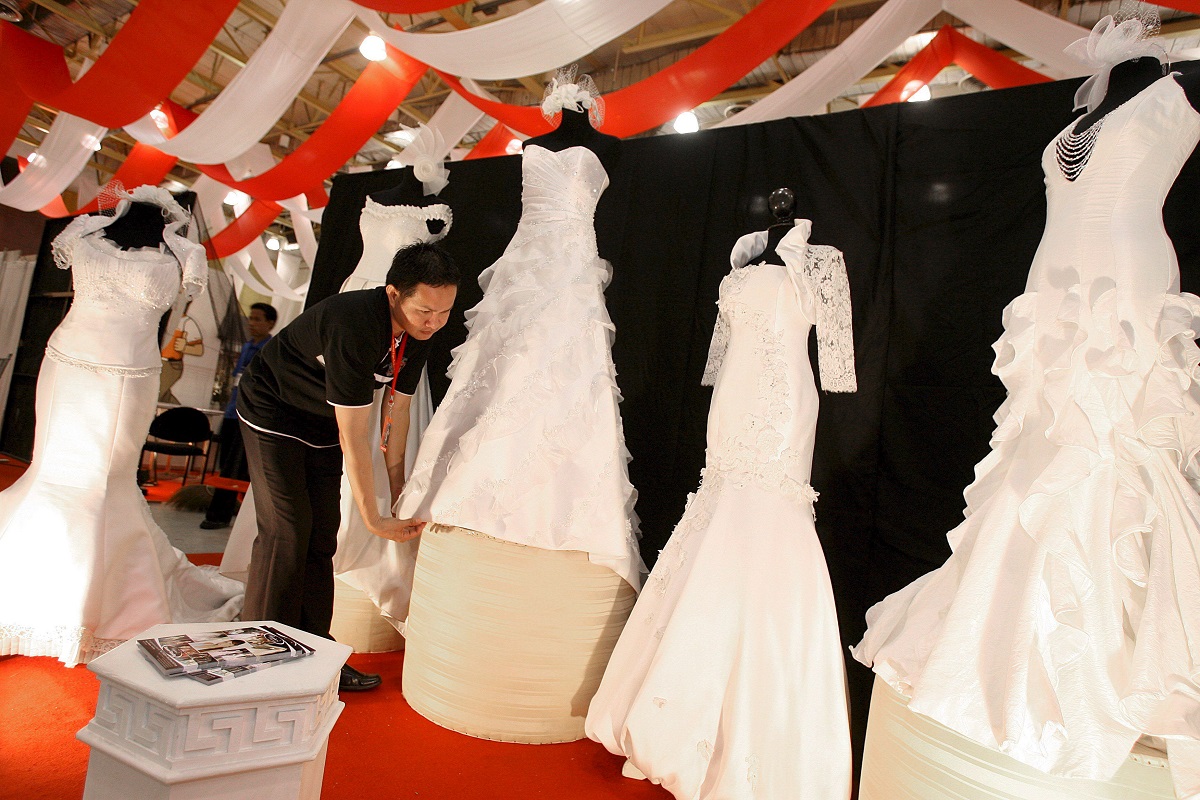 Un expositor de la feria coloca vestidos de novia en una Exposición de Bodas