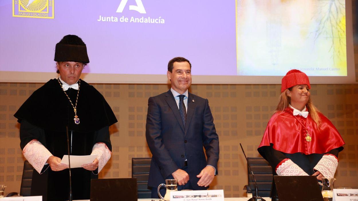 El presidente de la Junta de Andalucía, Juanma Moreno (c) y el rector de la UPO, Francisco Oliva (i), durante el acto de inicio del curso académico 2025-26 de las universidades andaluzas / EP