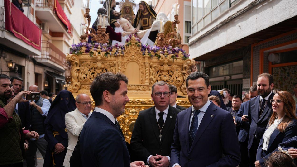 El presidente de la Junta de Andalucía, Juanma Moreno (d), ante el paso de la Virgen de La Piedad, durante la visita institucional al municipio de Cabra / EP