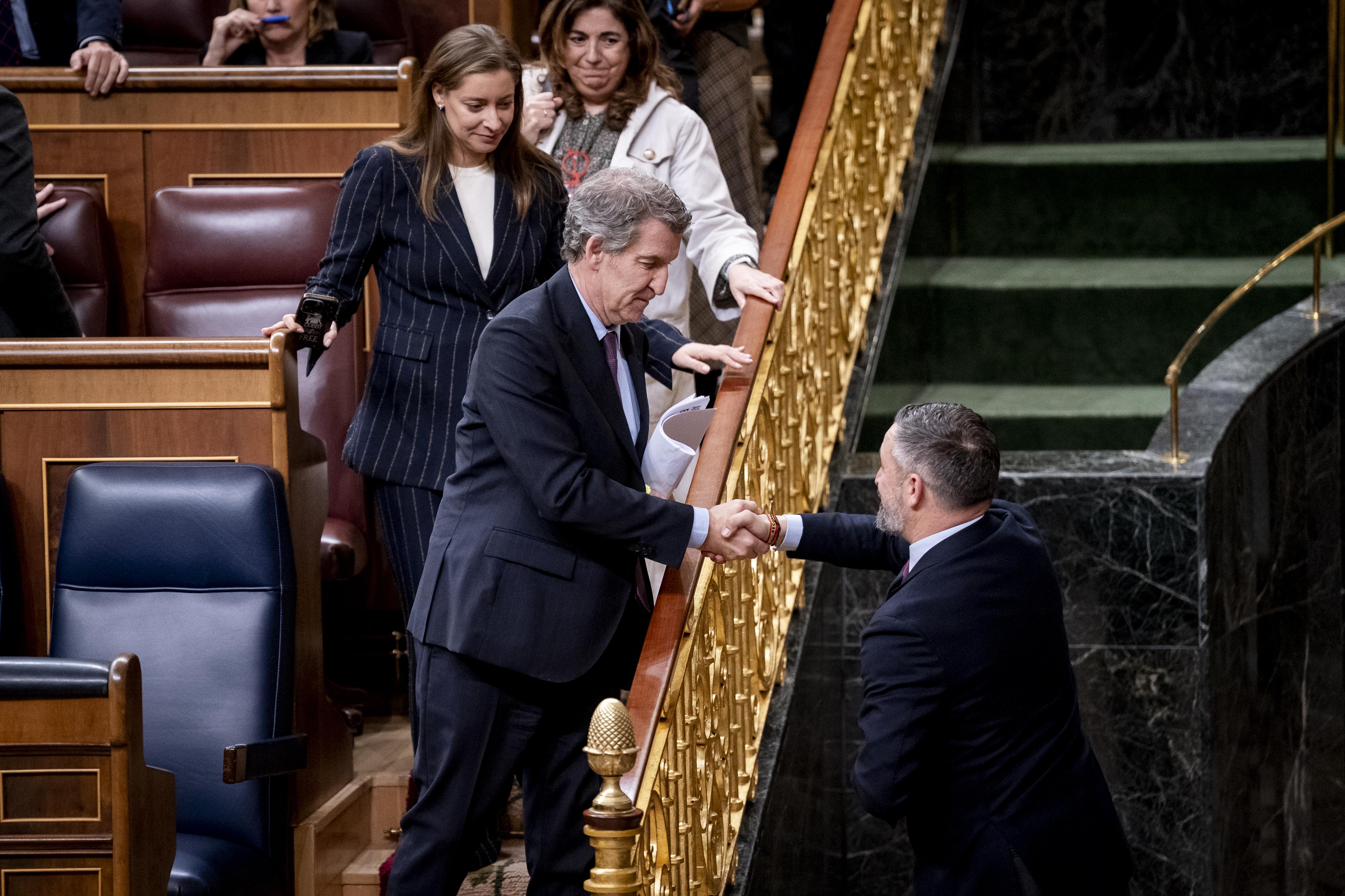 El presidente del Partido Popular, Alberto Núñez Feijóo, saluda al presidente de VOX, Santiago Abascal, a su salida de un pleno en el Congreso de los Diputados