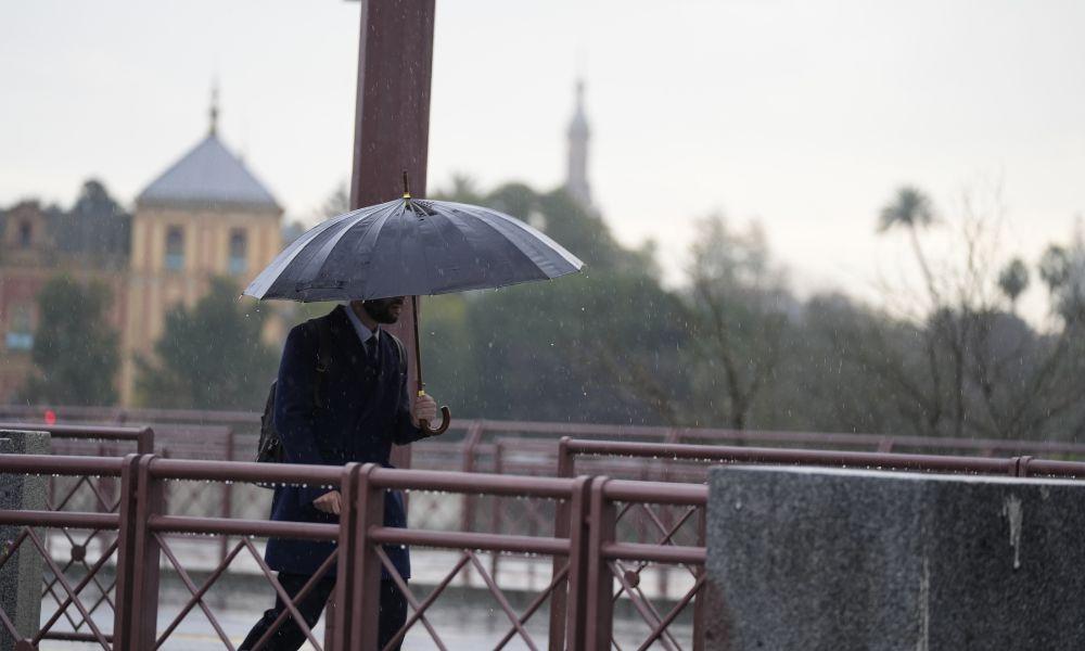 Una persona se protege de la lluvia con un paraguas. EP.