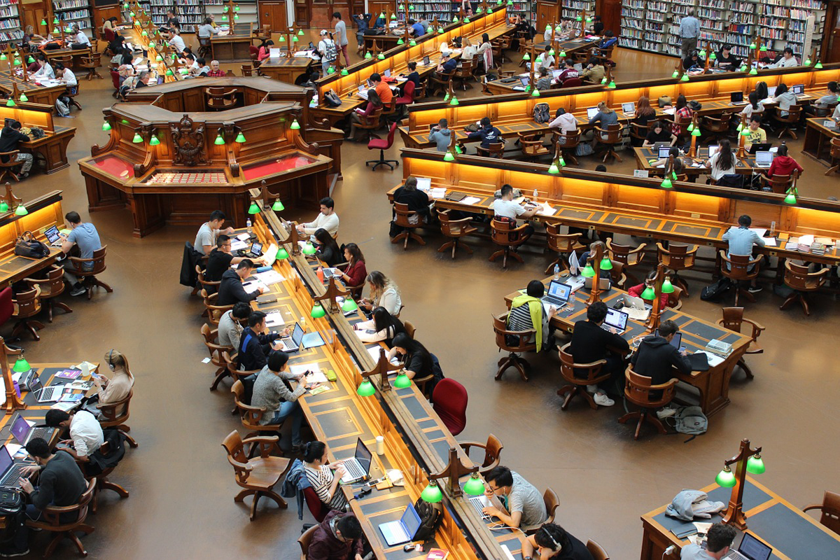Decenas de estudiantes en una biblioteca.