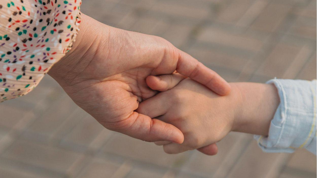Madre coge de la mano a su hijo pequeño. Imagen de archivo de Canva.