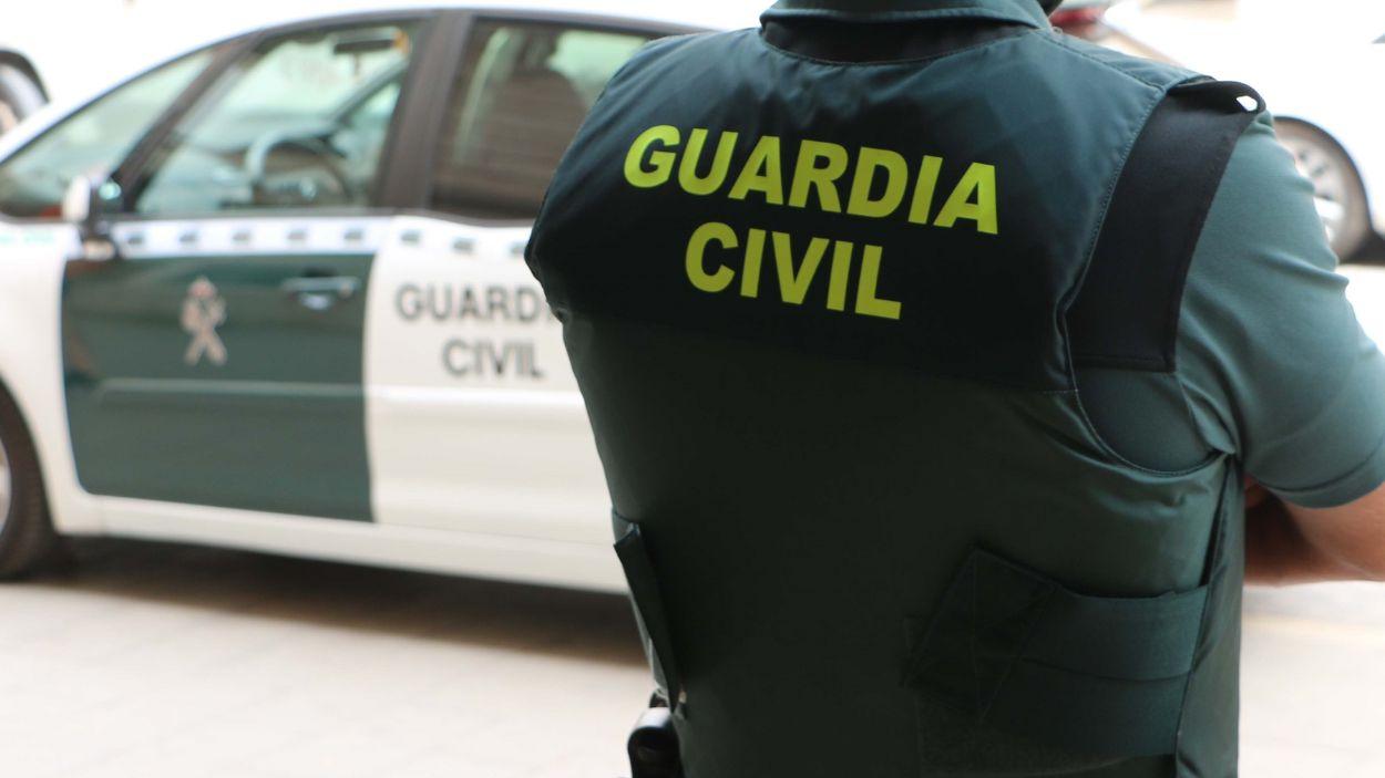 Agente de la Guardia Civil junto a un vehículo del instituto armado. EP.