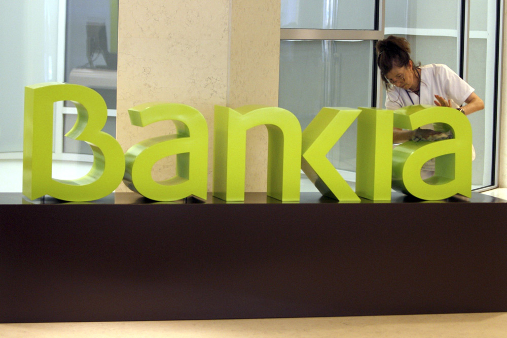 Una operaria limpia el logo de Bankia. 
