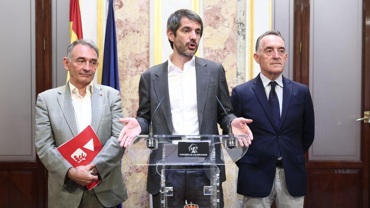 El portavoz parlamentario de Izquierda Unida, Enrique Santiago (i), el ministro de Cultura, Ernest Urtasun (c), y el portavoz de la comisión constitucional del PSOE, Artemi Rallo (d), durante una rueda de prensa. EP.