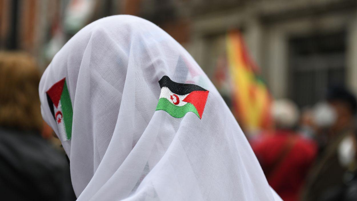 Una manifestante con un pañuelo blanco, con banderas sarahuis, en una manifestación convocada por la Coordinadora Estatal de Asociaciones Solidarias con el Sáhara (CEAS-Sáhara), frente al Ministerio de Asuntos Exteriores, a 26 de marzo de 2022. EP.