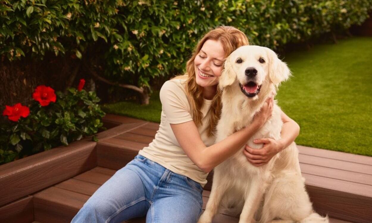 Una mujer sentada junto a un perro en una zona ajardinada. CAIXABANK