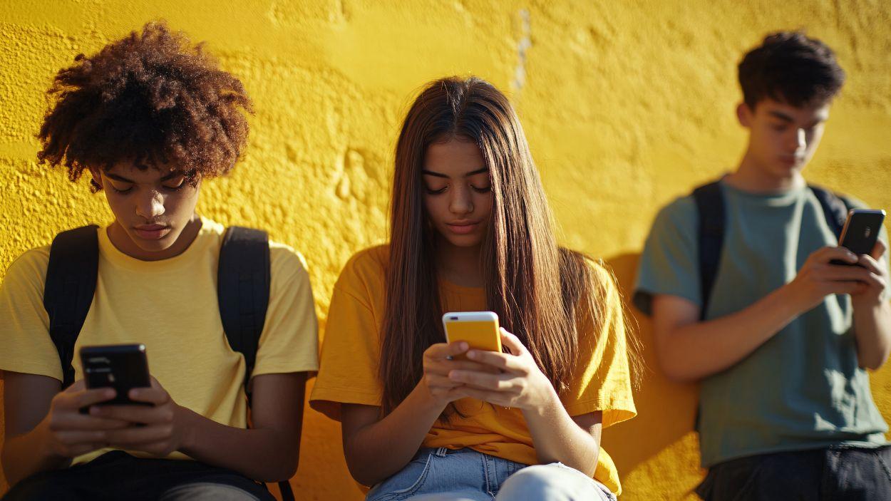 Adolescentes mirando sus teléfonos móviles.