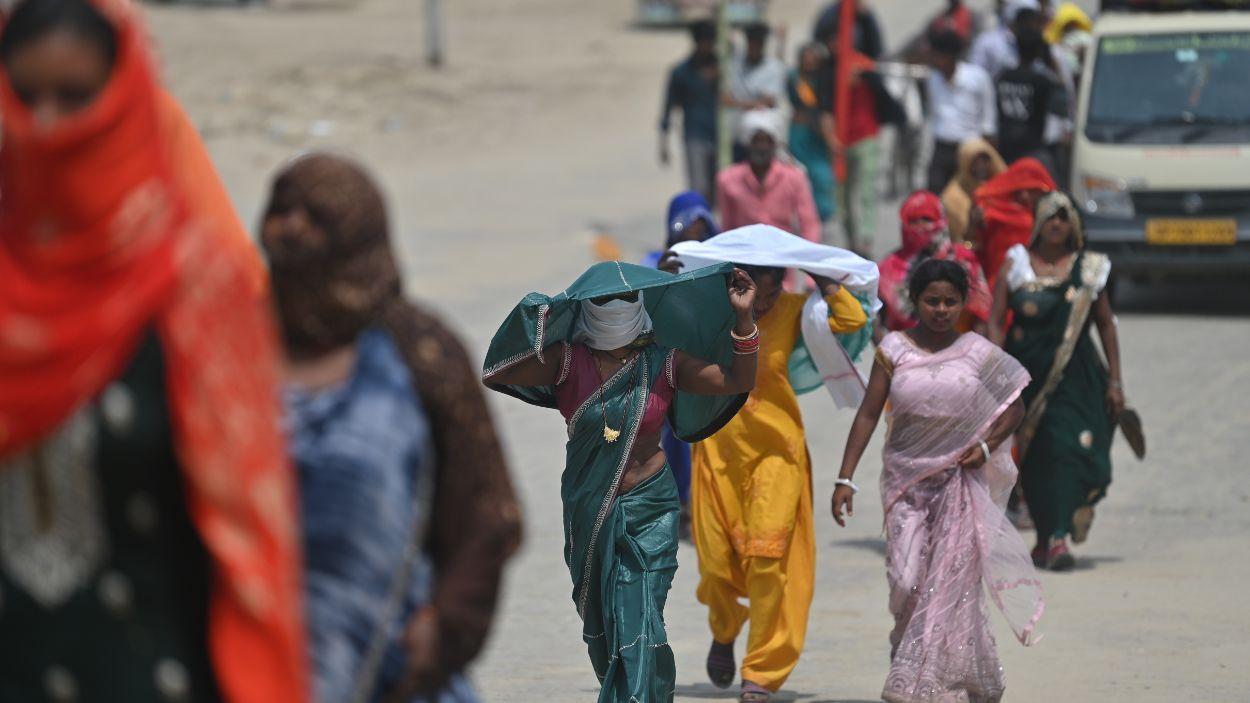 Personas se cubren con ropa para protegerse de la ola de calor en un caluroso día de verano, en Prayagraj (India). EP.