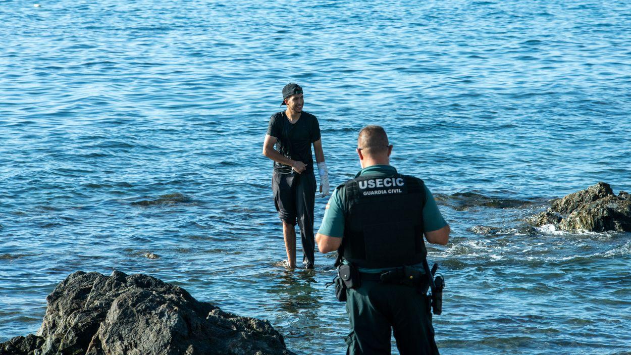 Imagen de un Guardia Civil frente a un migrante marroquí en aguas de Ceuta. EP.