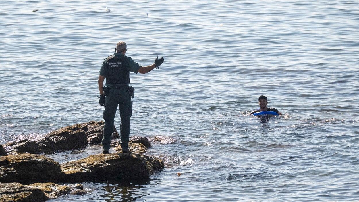 Un Guardia Civil frente a uno de los migrantes que llegó a nado a Ceuta. EP.