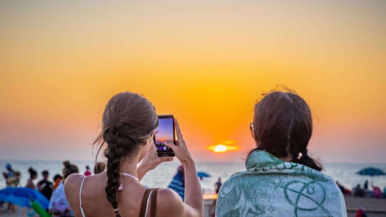 Dos jóvenes observan la puesta de sol en la playa de Camposoto, en San Fernando (Cádiz). EP.