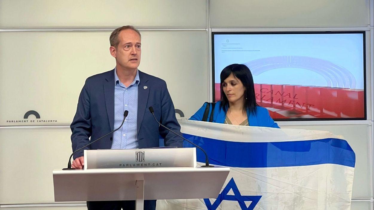 La líder de Aliança Catalana, Sílvia Orriols, con la bandera de Israel mientras otro miembro de su partido, Jordi Coma, habla en una rueda de prensa en el Parlament, a 21 de mayo de 2025. Foto de ARCHIVO / EP