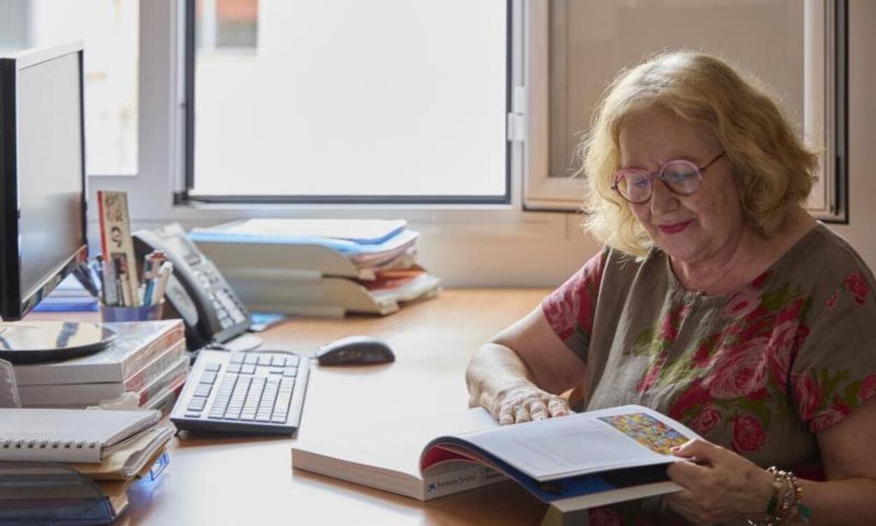 Persona mayor en un escritorio ojeando un libro. © Fundación "la Caixa"