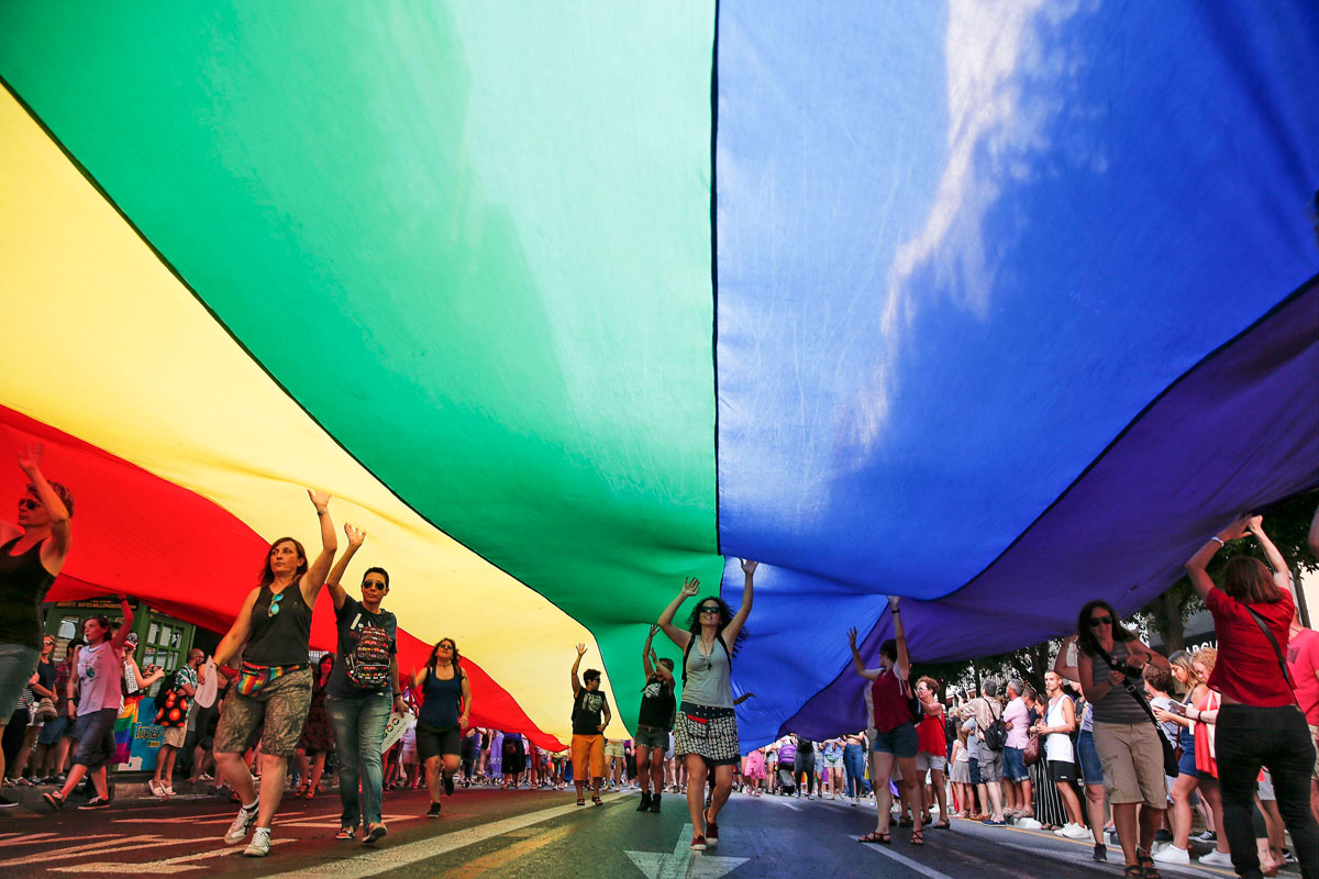Varias personas portan una bandera arcoríris gigante